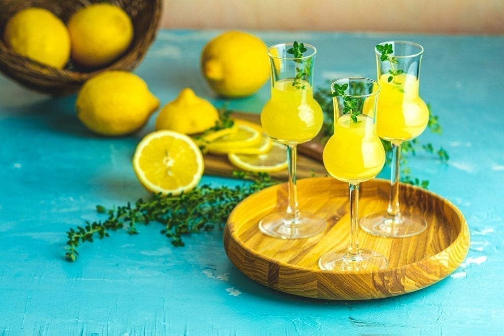 三杯柠檬酒，柠檬为背景，是意大利最好的纪念品之一