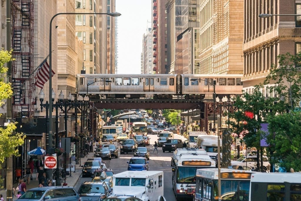 芝加哥火车在桥上驶过汽车交通的照片——在芝加哥必威体育官方登录周末度假时，乘坐芝加哥的公共交通工具是出行的最佳方式!