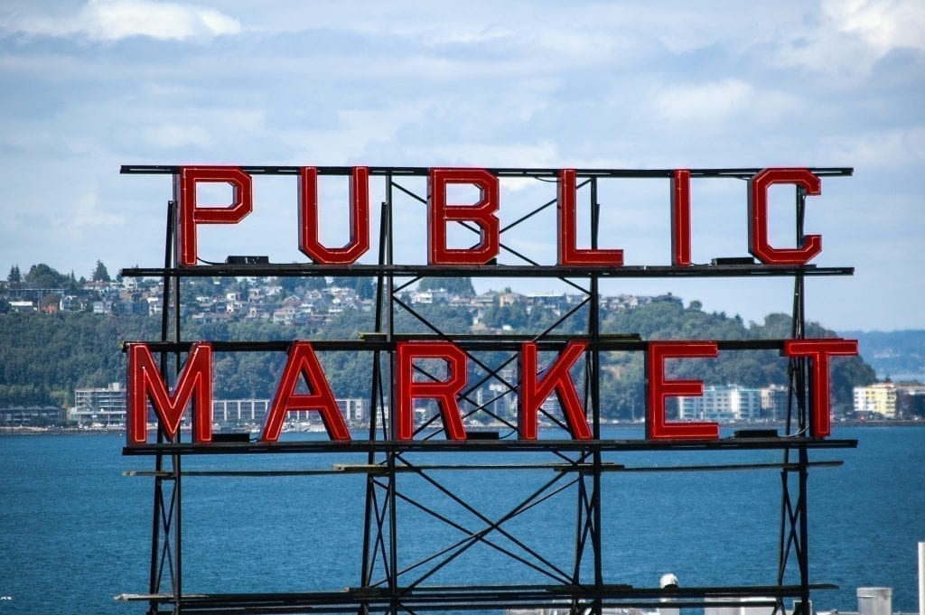 西雅图公共市场红色标志，背景中可见海洋。派克市场是在华盛顿西雅图徒步3天的必经之站!