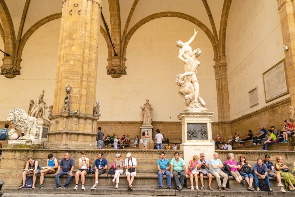 游客们坐在领主广场的雕像前，这被视为佛罗伦萨行程的一部分