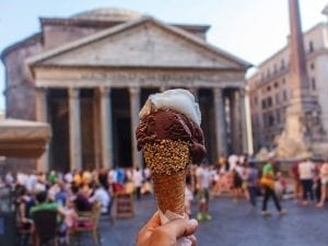 在罗马万神殿前，人们举着一个锥形冰淇淋。在意大利罗马，冰淇淋绝对是一种受欢迎的食物，可以考虑在罗马吃什么!