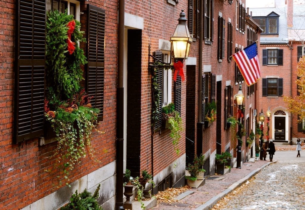 马萨诸塞州波士顿的橡果街，左边的建筑上悬挂着圣诞装饰，远处是一面美国国旗。波士顿是美国最好的圣诞度假胜地之一