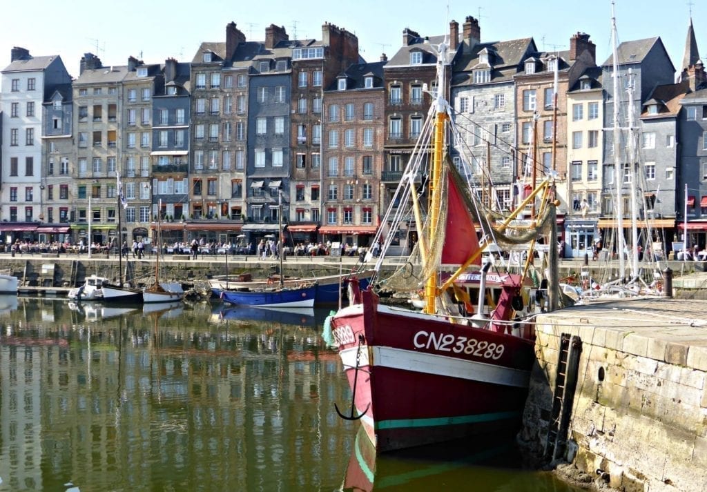 翁弗勒港，法国最美丽的小镇之一。前景是一艘红色的小船，背景是一排建筑物
