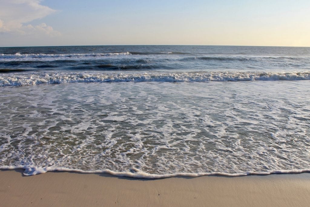 佛罗里达州的圣布拉斯角海滩，前景中可以看到金色的沙滩，背景中是接近海岸的波浪层。