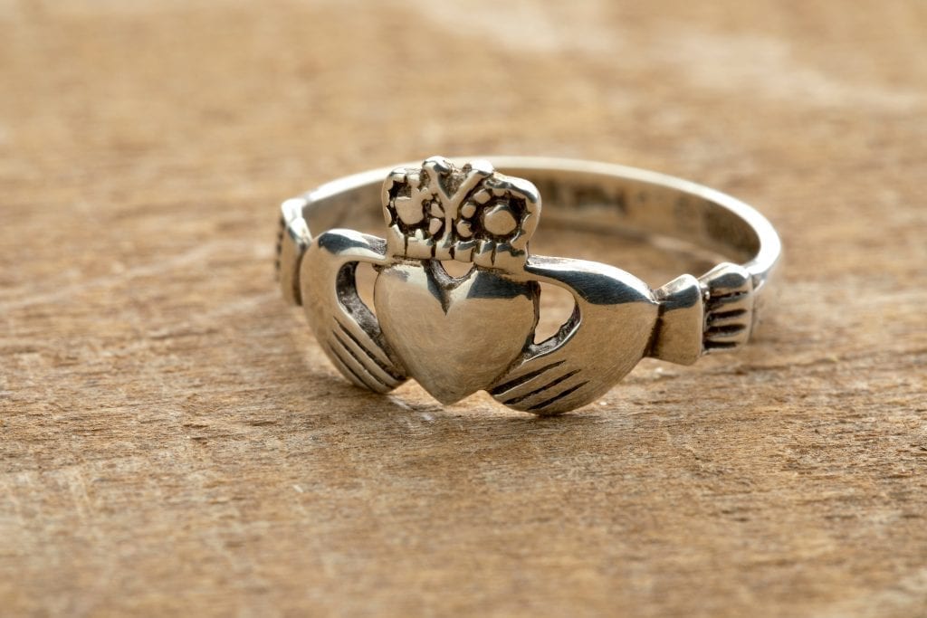 爱尔兰克拉达戒指放在木头表面上。当你决定在爱尔兰买什么时，考虑一下这枚传统戒指。