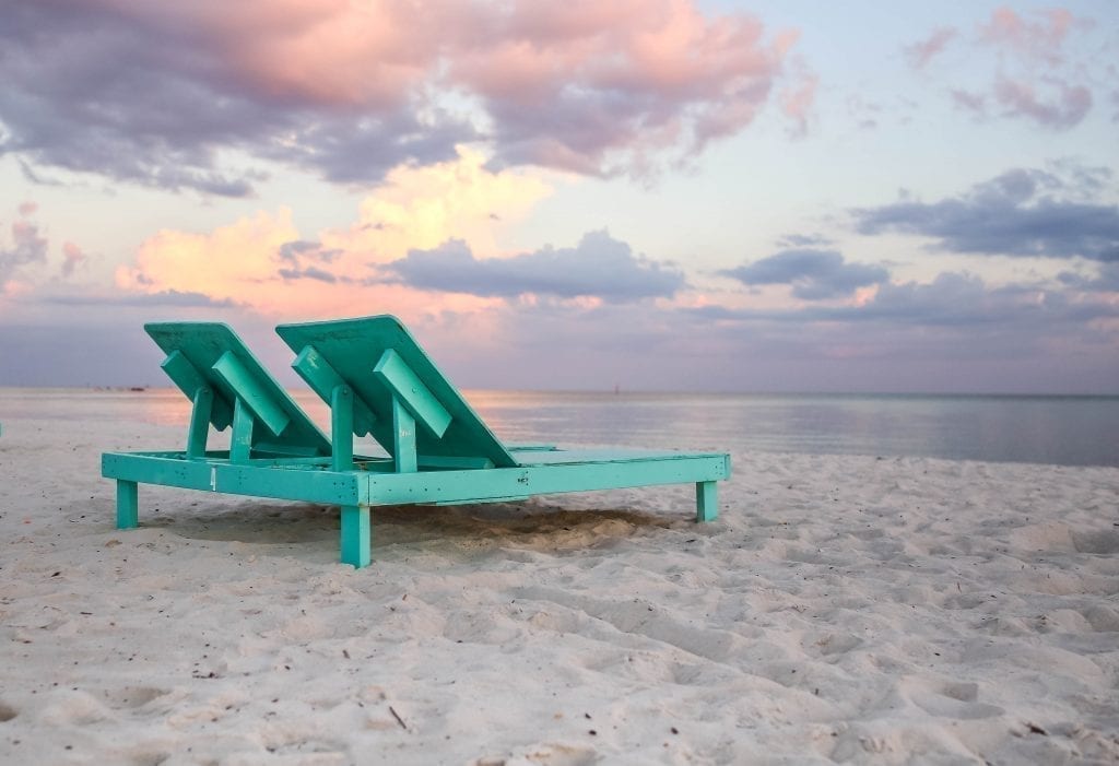 木制的藤条沙滩椅在日落时分的比洛克西海滩上，这是美国最好的白色沙滩之一