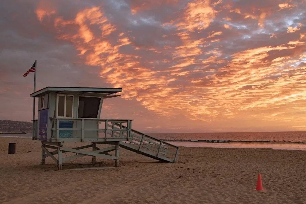 日落时分的洛杉矶赫莫萨海滩，照片左边站着一名救生员
