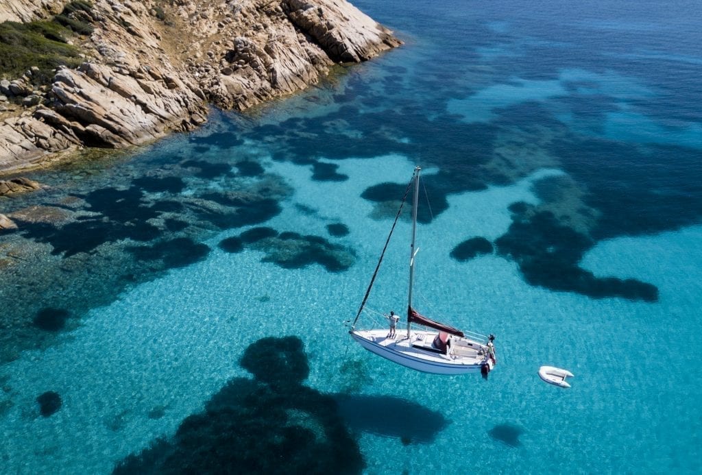 从上面看，白色帆船在撒丁岛周围清澈的蓝色大海中——撒丁岛是意大利最浪漫的地方之一