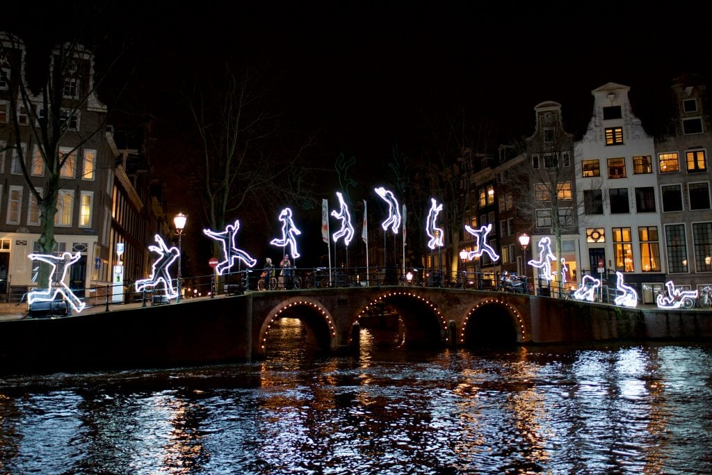 一个人在夜晚阿姆斯特丹的桥上在灯光下侧手翻