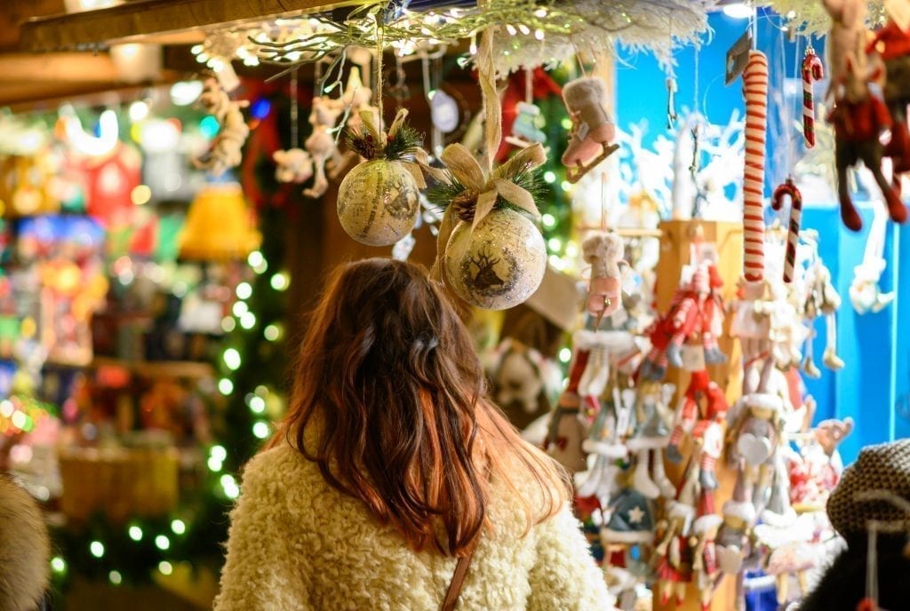 在欧洲圣诞市场上，深色头发的女人在卖饰品的摊位前购物