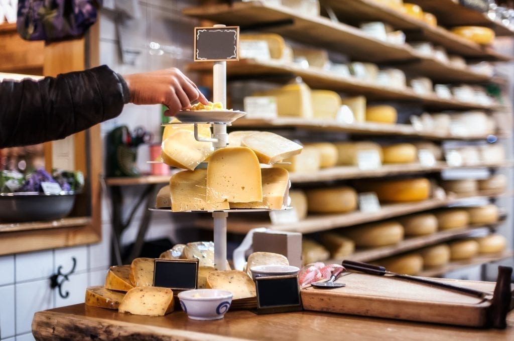 阿姆斯特丹出售的奶酪托盘，背景中可见满架子的奶酪轮子