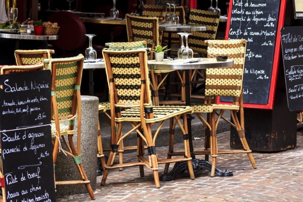 巴黎一家小餐馆的路边桌，可以看到2把椅子，旁边是菜单板
