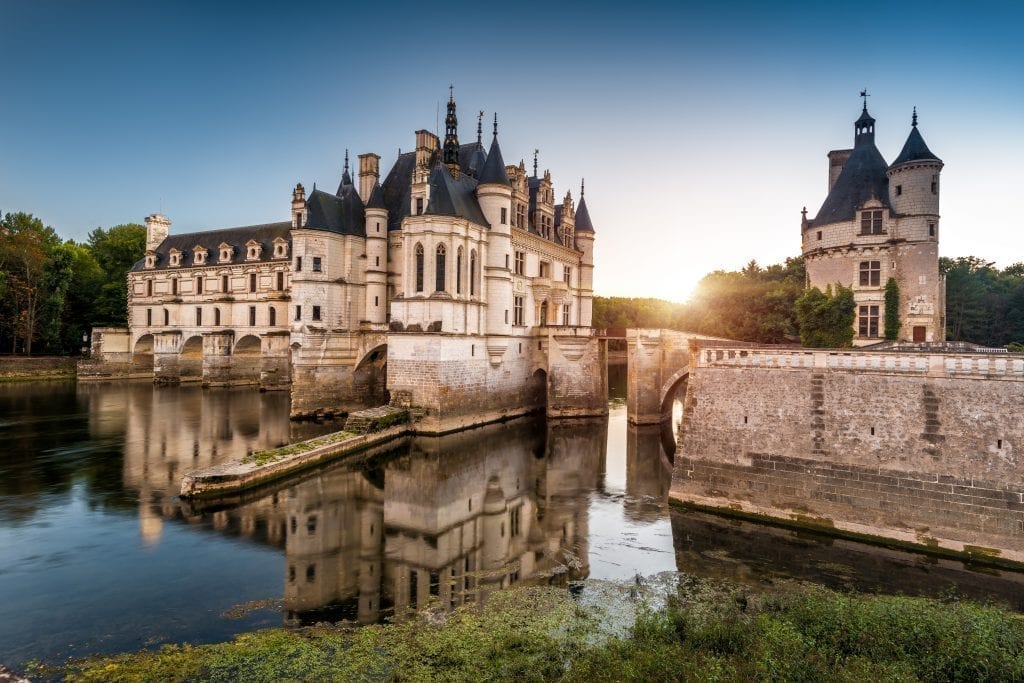 Château日落时从侧面看到的舍农索，前景是水。这座城堡是法国巴黎最好的一日游之一!