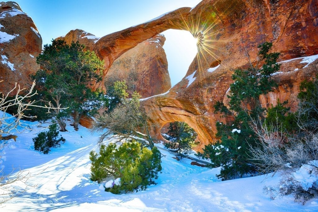 拱门NP中的拱门与太阳耀斑和地上的雪。冬季美国国家公园的拱门