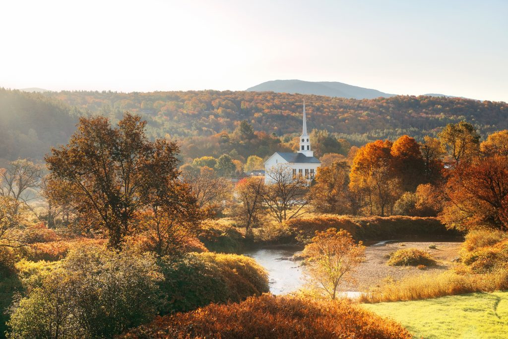 佛蒙特州斯托的白色教堂在秋天，被秋天的树叶包围
