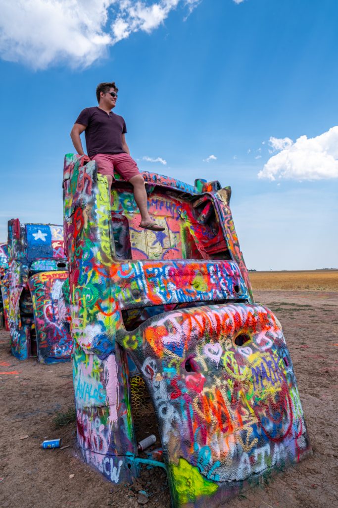 jeremy storm sitting on top of a car at cadillac ranch in amarillo