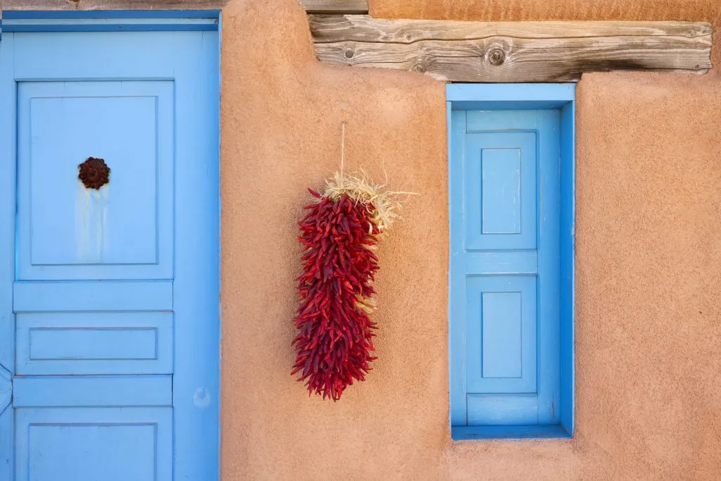 在新墨西哥州圣塔菲，挂在土坯建筑上的干辣椒有一个蓝色的门