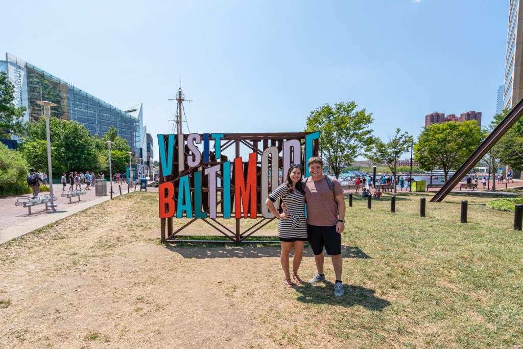 凯特·斯托姆和杰里米·斯托姆在马里兰州巴尔的摩周末度假时，摆出彩色的巴尔的摩参观标志