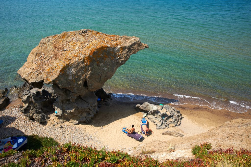 必威体育官方登录旅行者在希腊莱姆诺斯海岸的一块巨石附近晒太阳