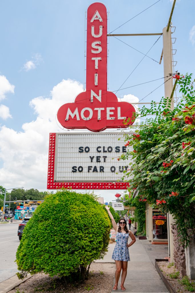凯特王妃穿着蓝白相间的裙子站在德克萨斯州奥斯汀市标志性的奥斯汀汽车旅馆招牌下
