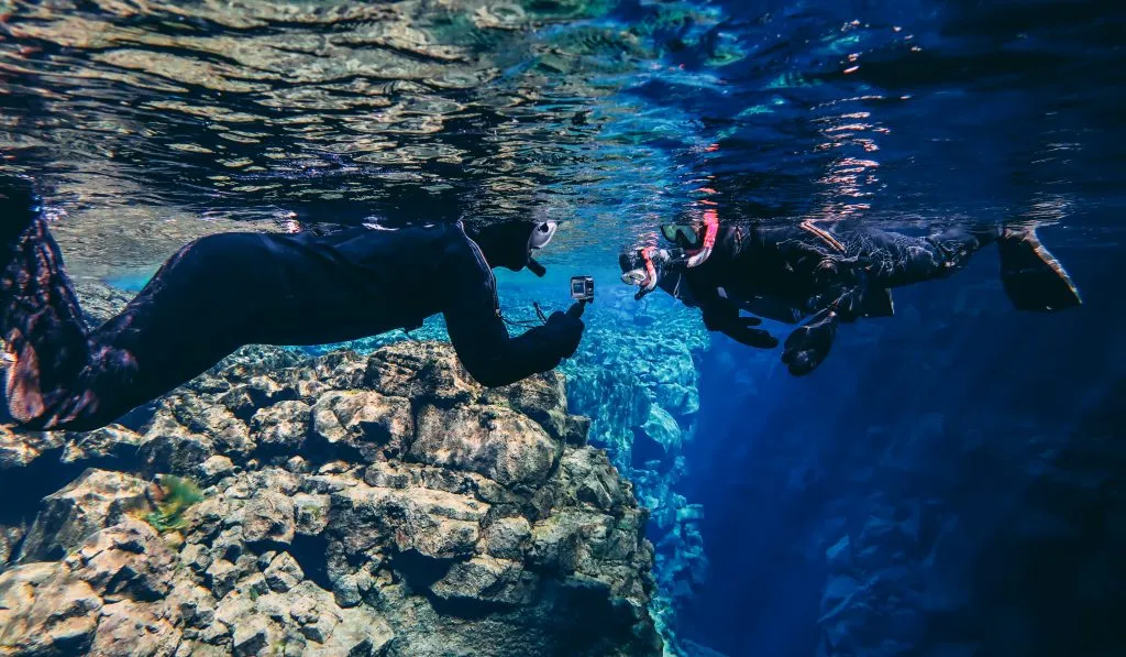 两个人在冰岛浮潜，一个人在给另一个人拍照