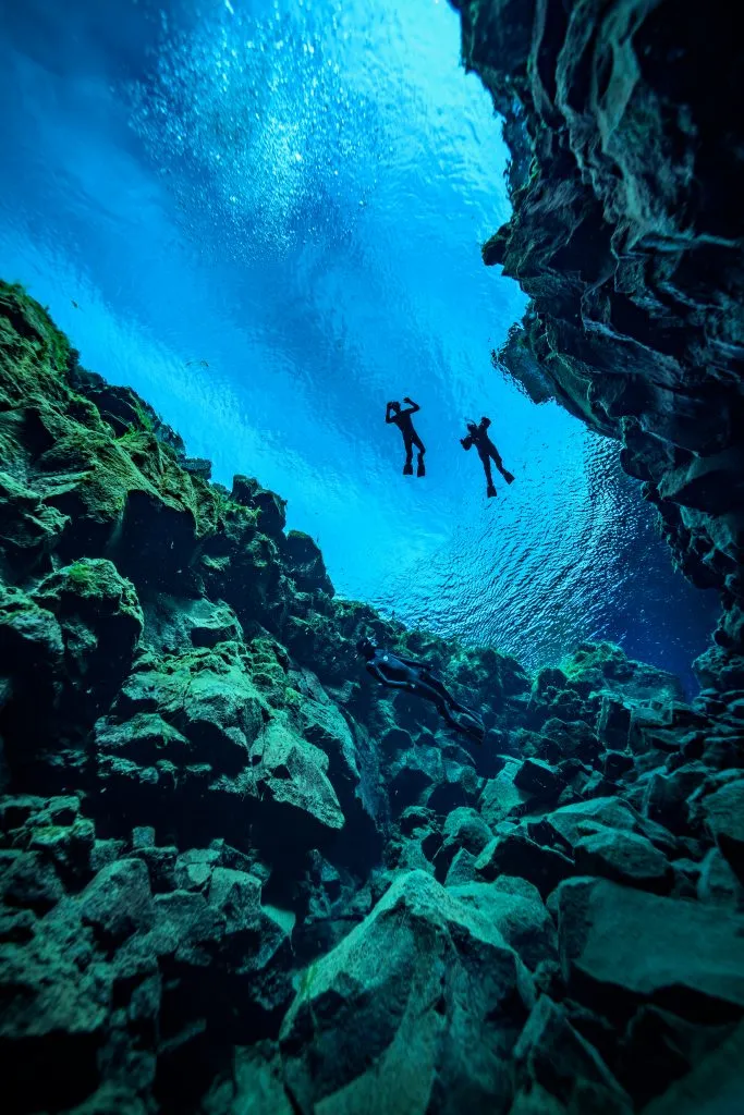 在冰岛，两个人从下面看到在银叶海上浮潜
