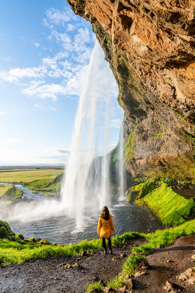 凯特在seljalandsfoss面前穿着一件黄色夹克，计划去冰岛旅行