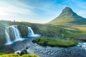 在一个阳光明媚的夜晚，Kirkjufell瀑布是计划去冰岛旅行最梦想的地方之一