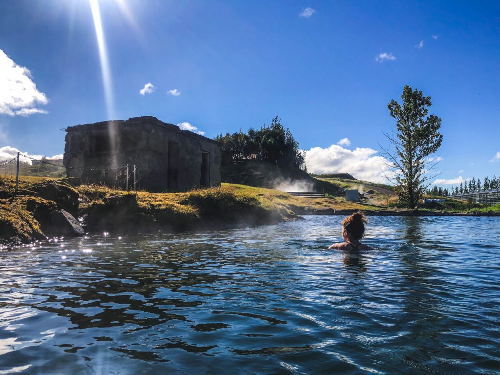 在阳光明媚的日子里，人们泡在冰岛的秘密泻湖里，这是冰岛最好的活动之一