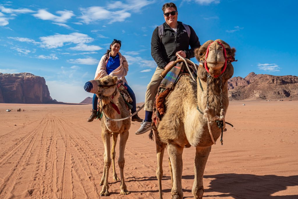 凯特·斯托姆和杰里米·斯托姆在约旦河露营时骑着骆驼