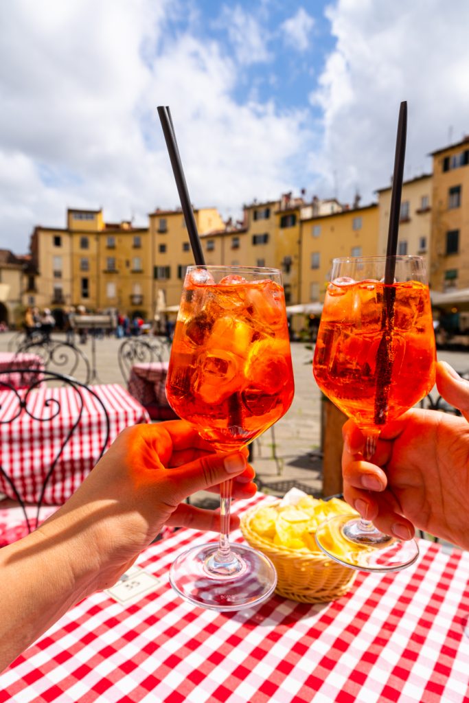 在意大利卢卡最好的旅游景点之一的戴尔安菲特罗广场上，人们举起两杯aperol酒