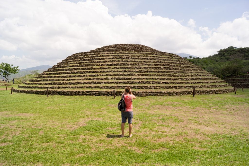 一名男子站在瓜奇蒙顿金字塔前拍照