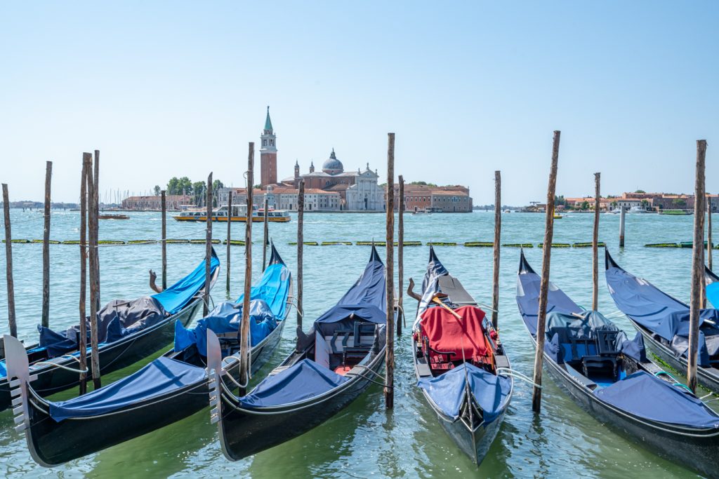 在夏天的意大利威尼斯，停在泻湖上的贡多拉以圣乔治马焦雷为背景