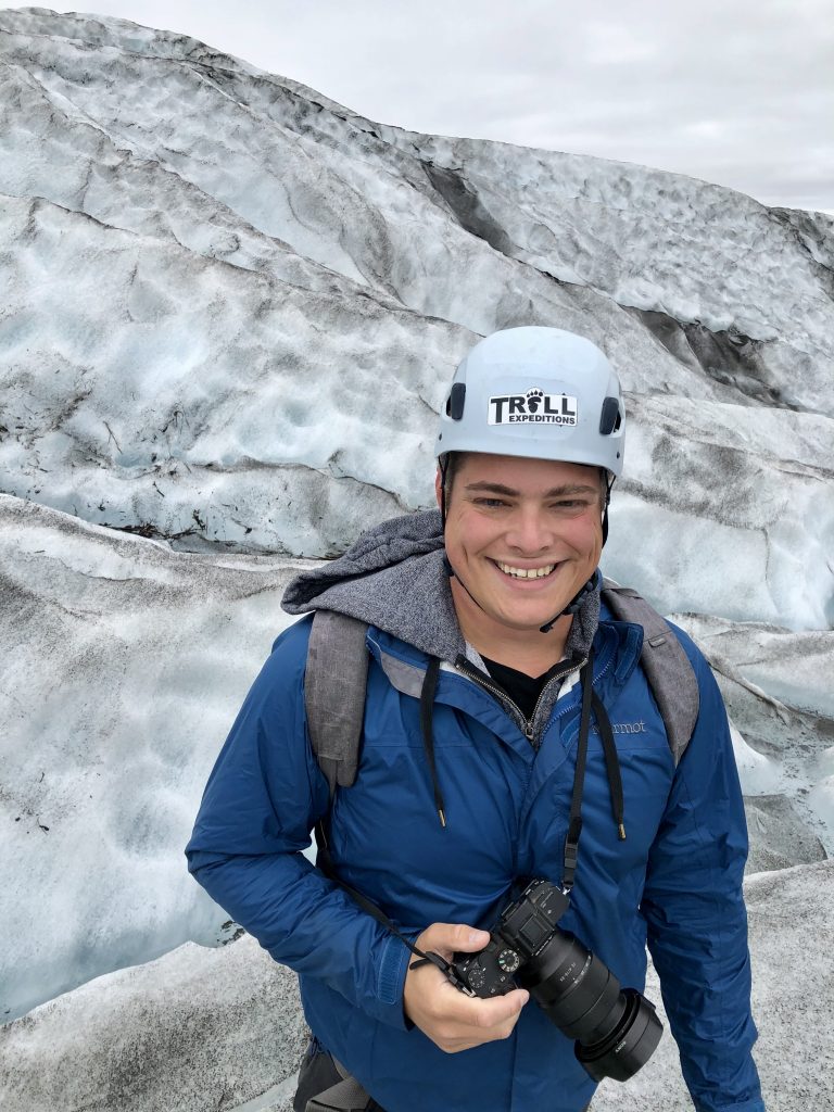 杰里米·斯托姆拿着相机微笑着走在冰岛冰川上