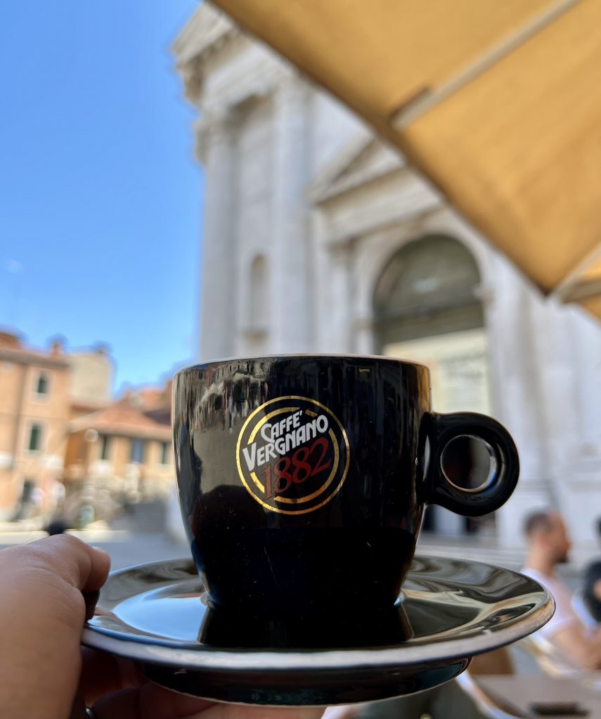在威尼斯圣巴纳巴广场上，人们举起一杯黑色的意大利咖啡