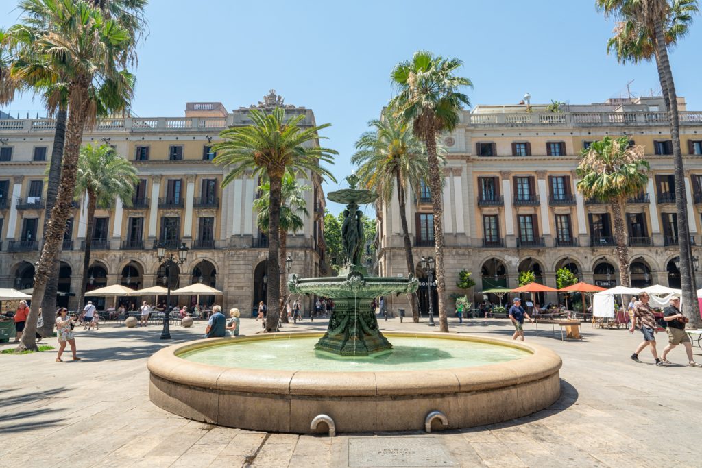 placa reial in barcelona spain with a fountain surrounded by palm trees