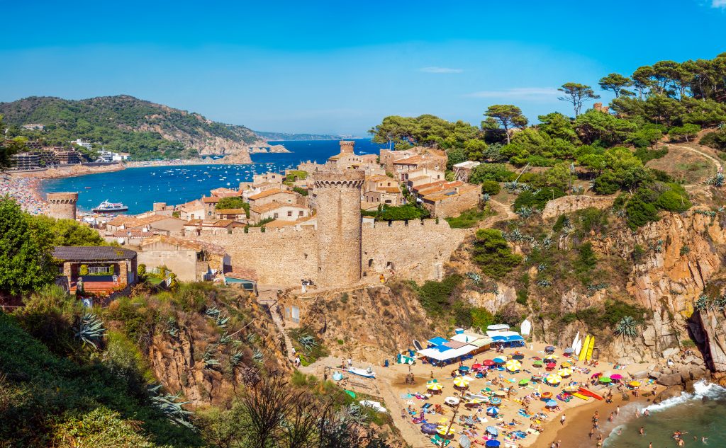 tosa de mar，前景是海滩，背景是城堡，是西班牙最美丽的海滨城镇之一