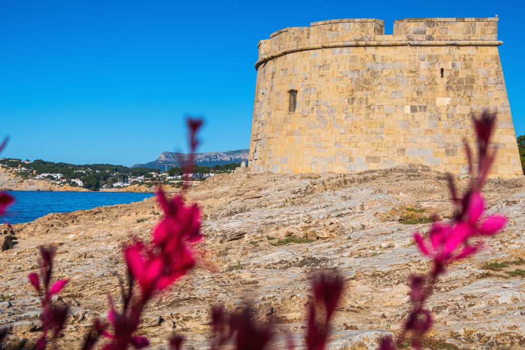 前景是粉红色花朵的Moraira城堡