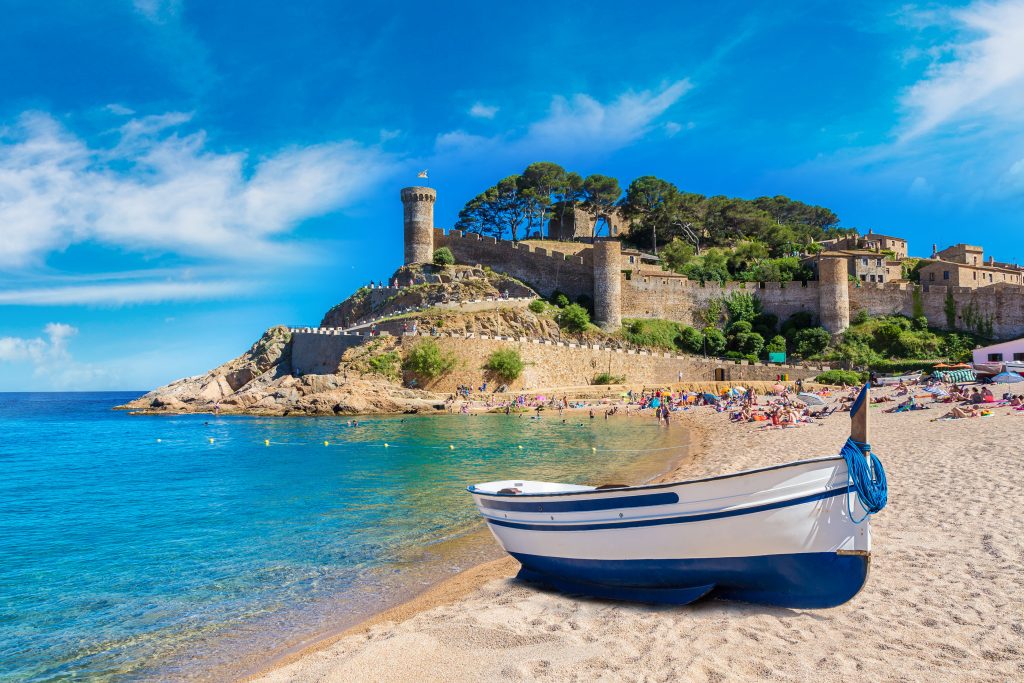 美丽的西班牙布拉瓦海岸海滩，前景是船，背景是城堡