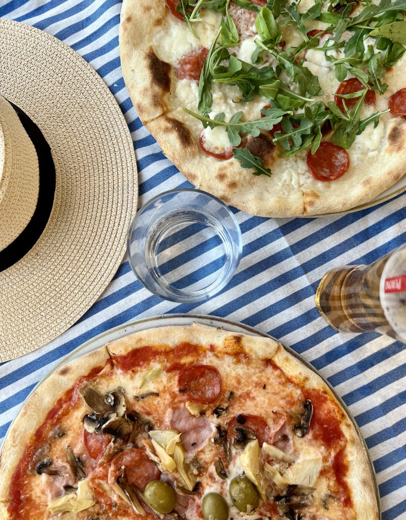 意大利餐厅的两份披萨套餐，一顶太阳帽和啤酒