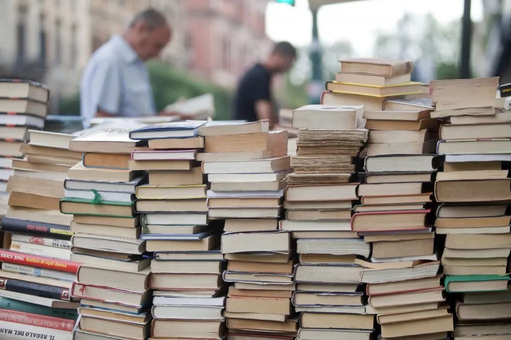 意大利罗马，一堆待售的书，背景是两个男人在看书