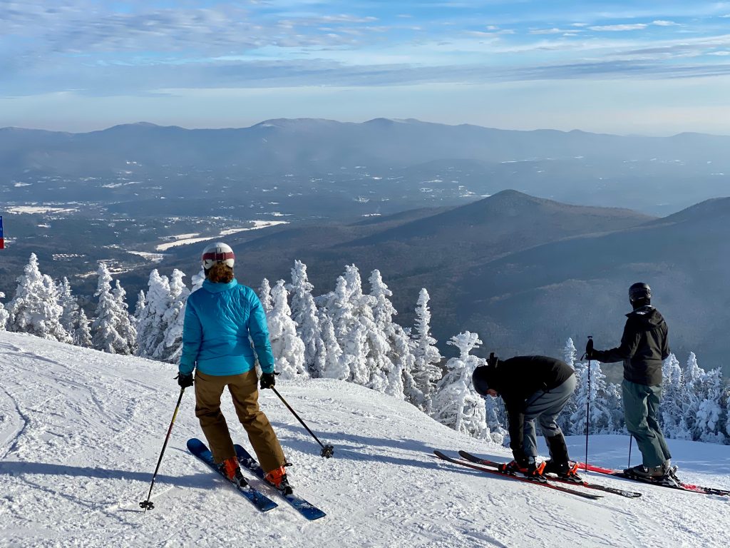 三名滑雪者在佛蒙特州的山上滑雪，佛蒙特州是美国冬季最好的旅游胜地之一