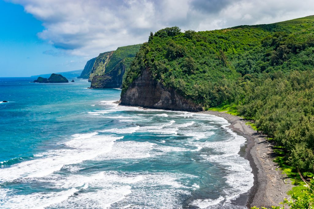夏威夷大岛的壮丽海岸线和前景中的海滩，是美国最好的暖冬度假胜地之一