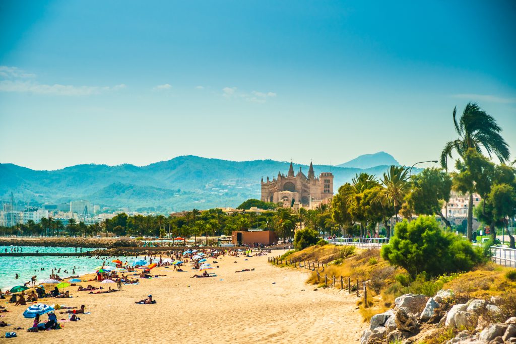 西班牙帕尔马的海滩，前景是沙子，背景是大教堂