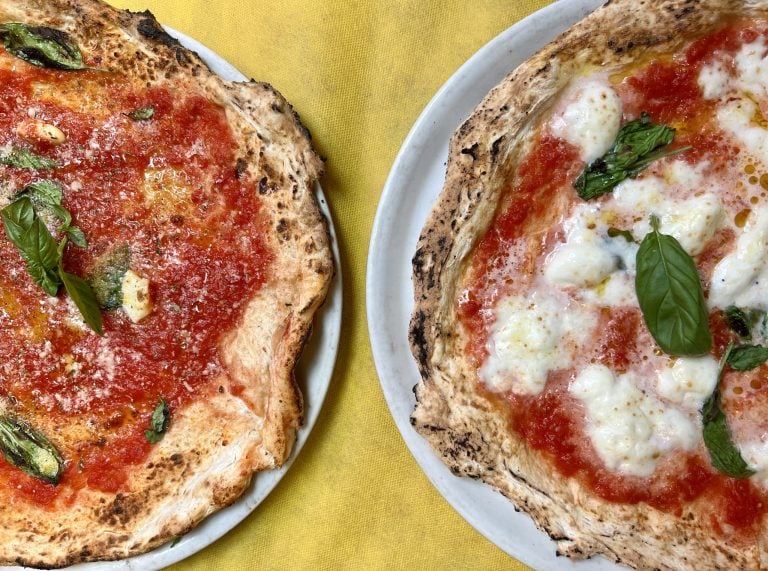 意大利一家披萨店的桌子上，马里纳拉披萨和玛格丽塔披萨并排摆放